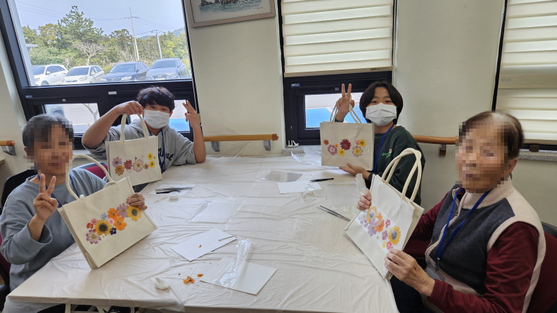 어르신과 학생이 함께 만든 압화에코백 들고 있는 모습