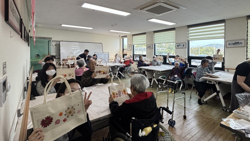 어르신과 학생들이 함께 만든 압화에코백 들고 있는 모습