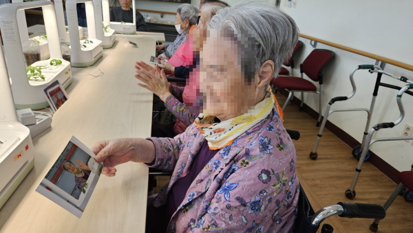 식물과 같이 찍은 사진을 보고 미소지으시는 어르신 모습
