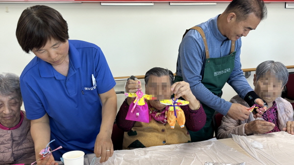 한복모양의 향주머니를 양손에 들고 있는 어르신
