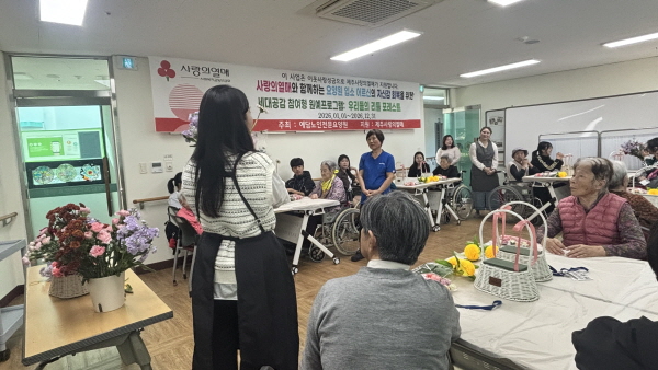원예치료 강사분이 꽃에 대해 설명하고, 어르신들과 학생들이 듣고 있는 모습