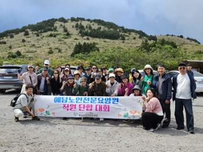 오름을 배경으로 현수막 들고 단체사진 찍는 모습