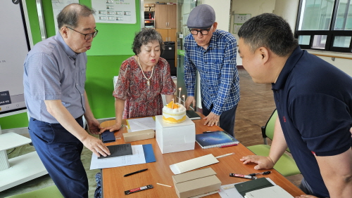 4명이 둘러 모여 케이크에 불을 끄는 모습