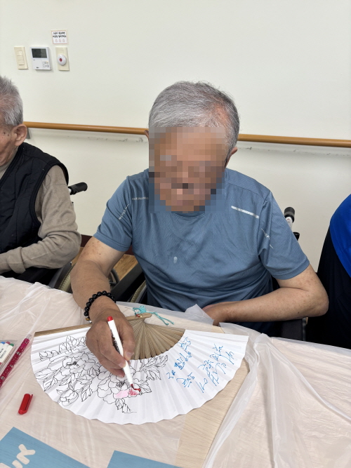 남자 어르신이 부채에 그림 그리고 있는 모습