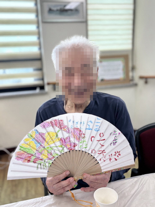 남자 어르신이 부채를 들고 환히 웃고 계신 모습