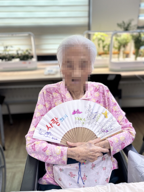여자 어르신이 부채를 들고 웃고 계신 모습