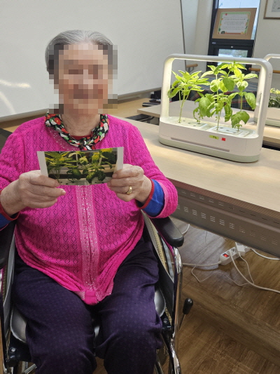 여자 어르신이 식물 사진을 들고 있는 모습