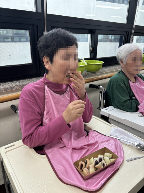 어르신이 떡을 입에 넣고 있는 모습