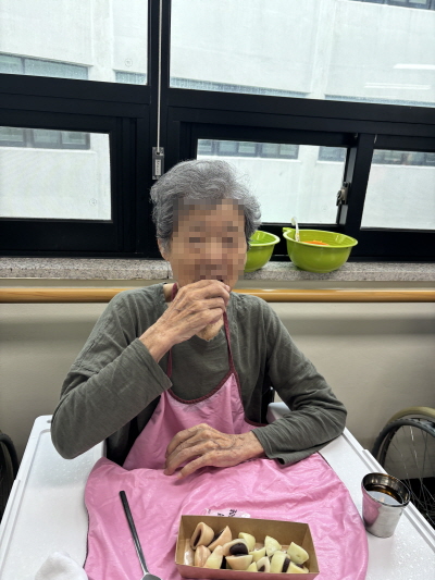 어르신이 떡을 입에 넣고 있는 모습