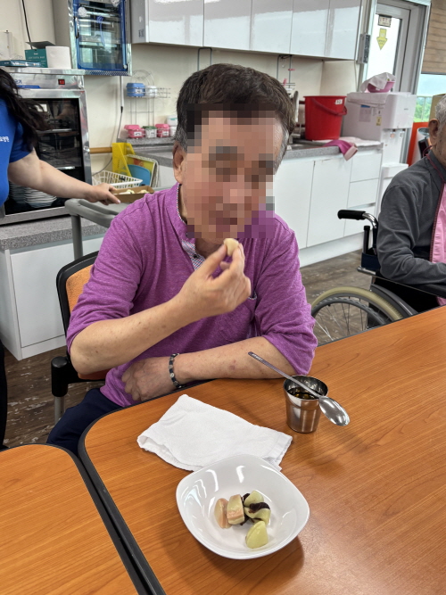 어르신이 떡을 입에 넣고 있는 모습