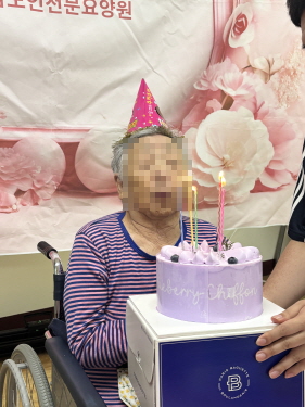 꼬깔모자쓴 여자 어르신이 생일케이크 촛불 부는 모습