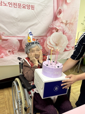 꼬깔모자쓴 여자 어르신이 생일케이크 촛불 부는 모습