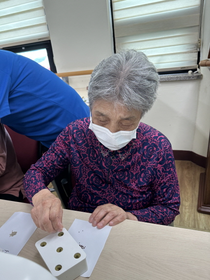 여자 어르신이 씨앗을 구멍에 넣고 있다