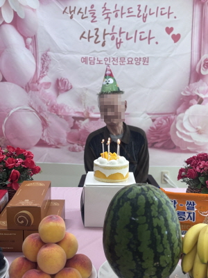 고깔모자를 쓴 남자 어르신이 생신상앞에 앉아 계시다