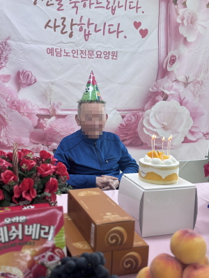 고깔모자를 쓴 남자 어르신이 생신상앞에 앉아 계시다