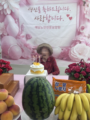 모자를 쓴 여자 어르신이 생신상앞에 앉아 계시다