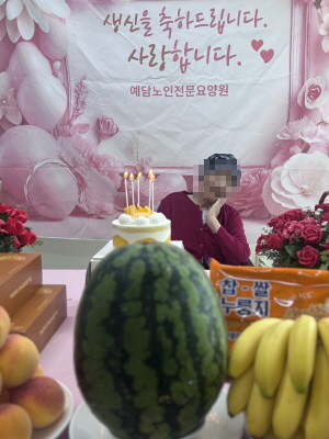 여자 어르신이 생신상앞에 앉아 계시다