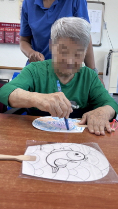 부채에 색칠하고 있는 여자 어르신