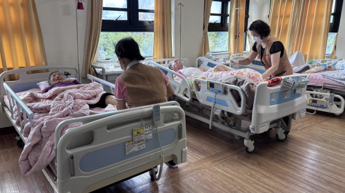 침대에 누워 계시는 어르신들 발마시지를 해주고 있다