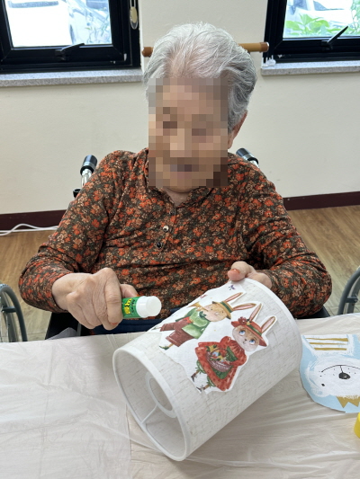 여자 어르신이 무드등에 풀을 붙이고 있다