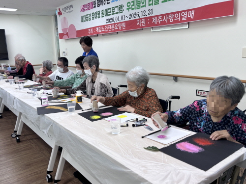 여러 명의 어르신들이 검은 도화지에 물감을 찍는 활동을 하고 있다.