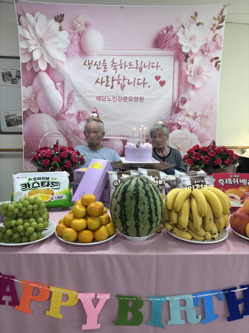 남자 어르신 1명과 여자 어르신 1명이 생신잔치상 앞에 앉아 있다
