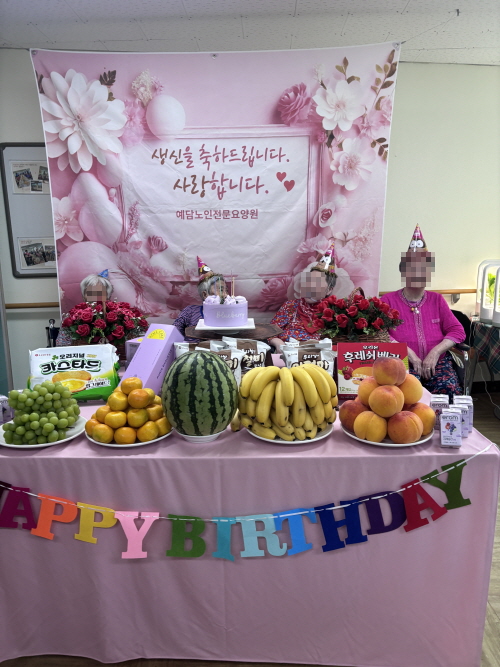여자 어르신 4명이 생신잔치상 앞에 앉아 있다